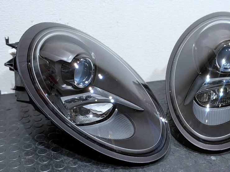 ポルシェ 991 のヘッドライト施工後。曇りがなくなり、黒いハウジングとプロジェクターレンズがくっきり見える